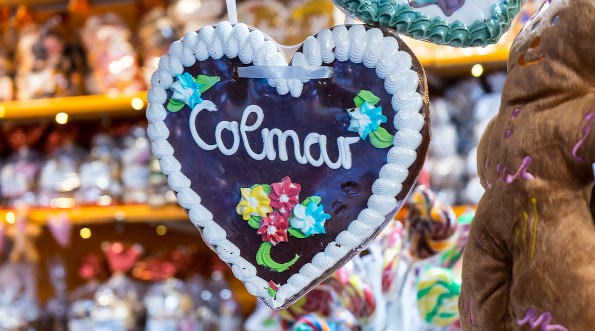 Decorated heart shaped biscuit with Colmar written in icing across middle